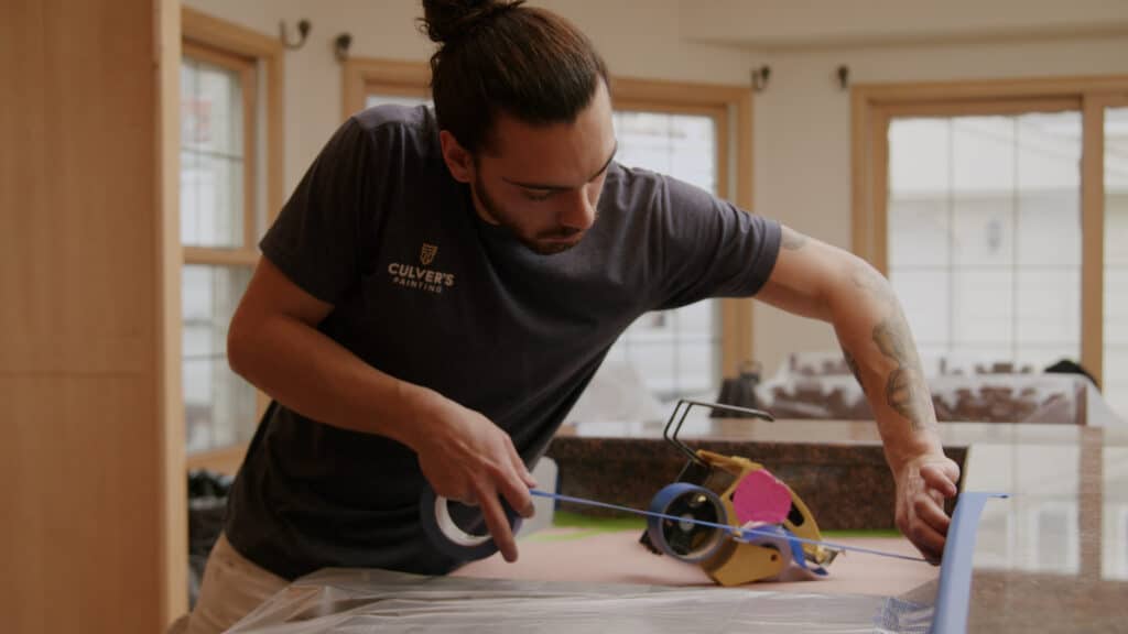 Craftsperson Justin expertly masks before cabinet painting